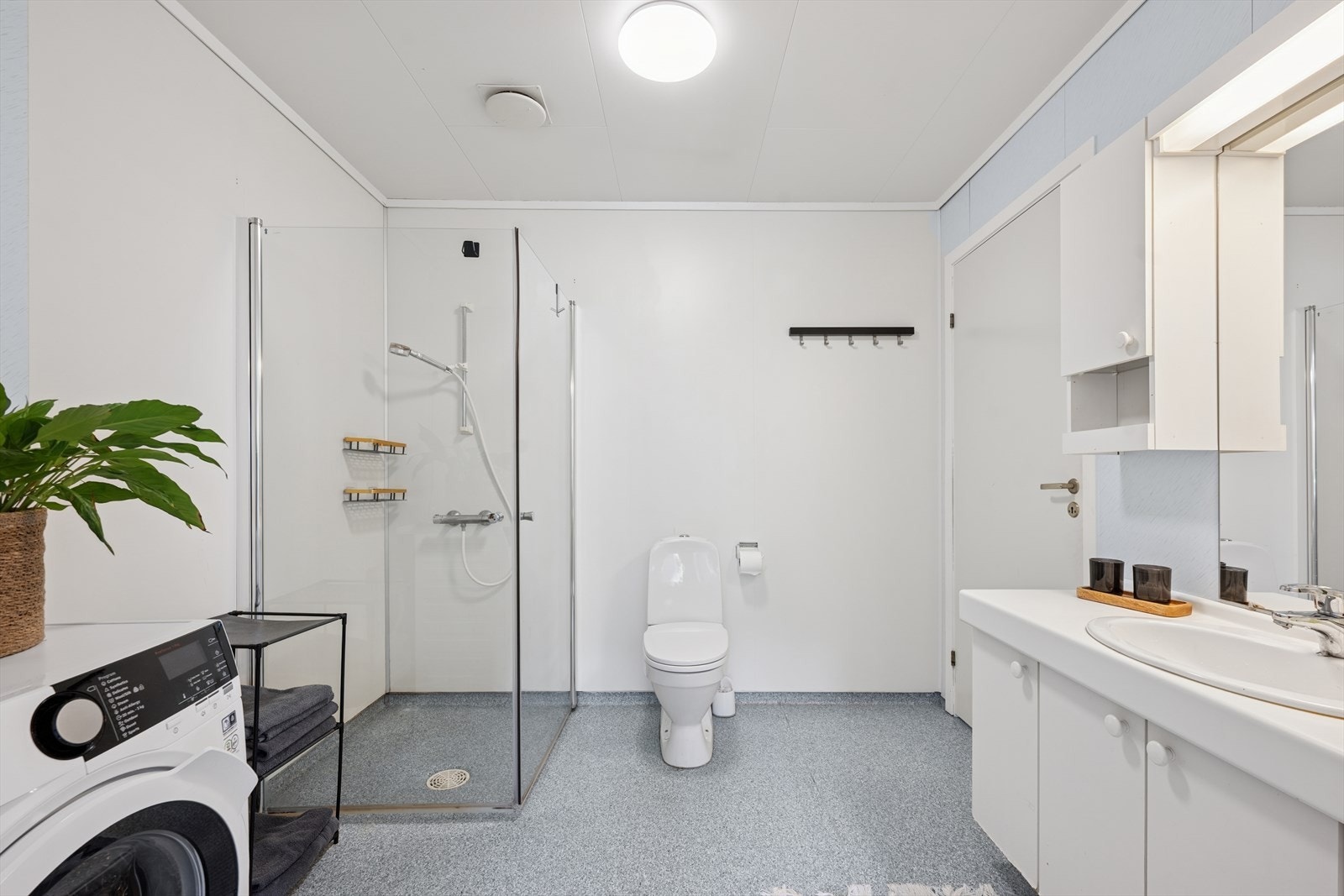 Badet er innredet med dusjdører, toalett og en moderne baderomsinnredning med servant og speil. Galleribilde