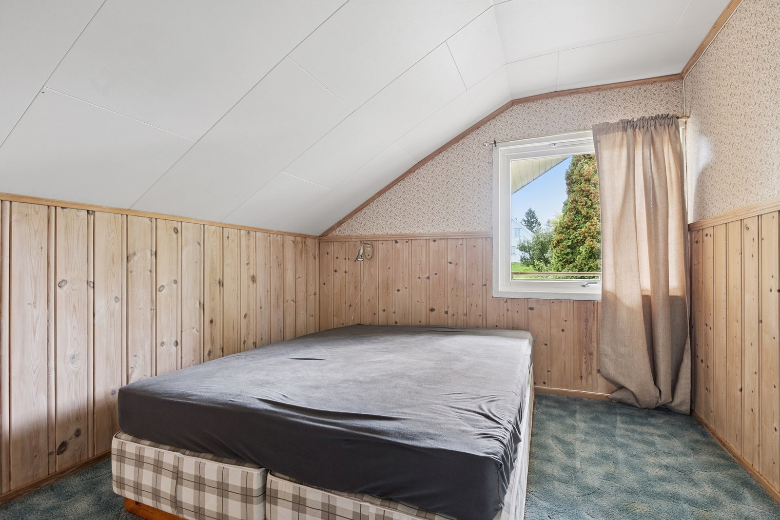Et koselig soverom med skråtak og trepanel. Galleribilde