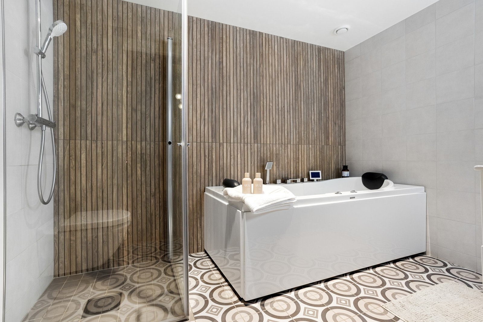 Bad med flislagte vegger og gulv, dusjnisje, vegghengt toalett og et Viking massasjebad som kan styres via panel Galleribilde