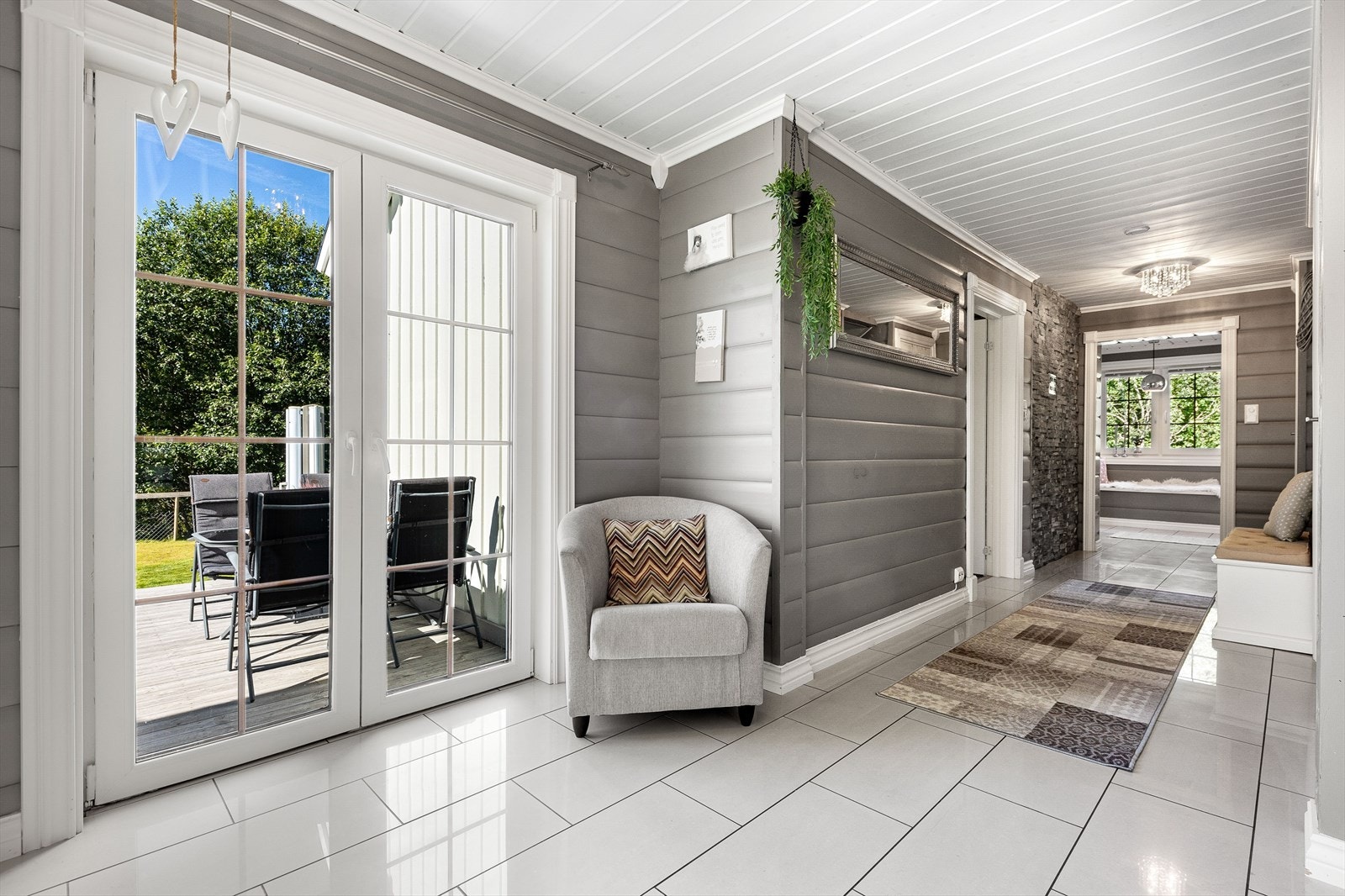 Fra overbygget inngangsparti, trer du inn i en lys entré. Fra entréen har du rett frem tilgang til gang som igjen leder videre til bad, soverom, stue og kjøkken. Dette er i boligens hoveddel Galleribilde