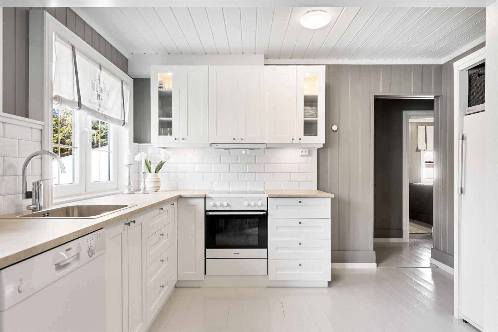 Tiltalende kjøkken med hvite, profilerte fronter og laminert benkeplate Galleribilde