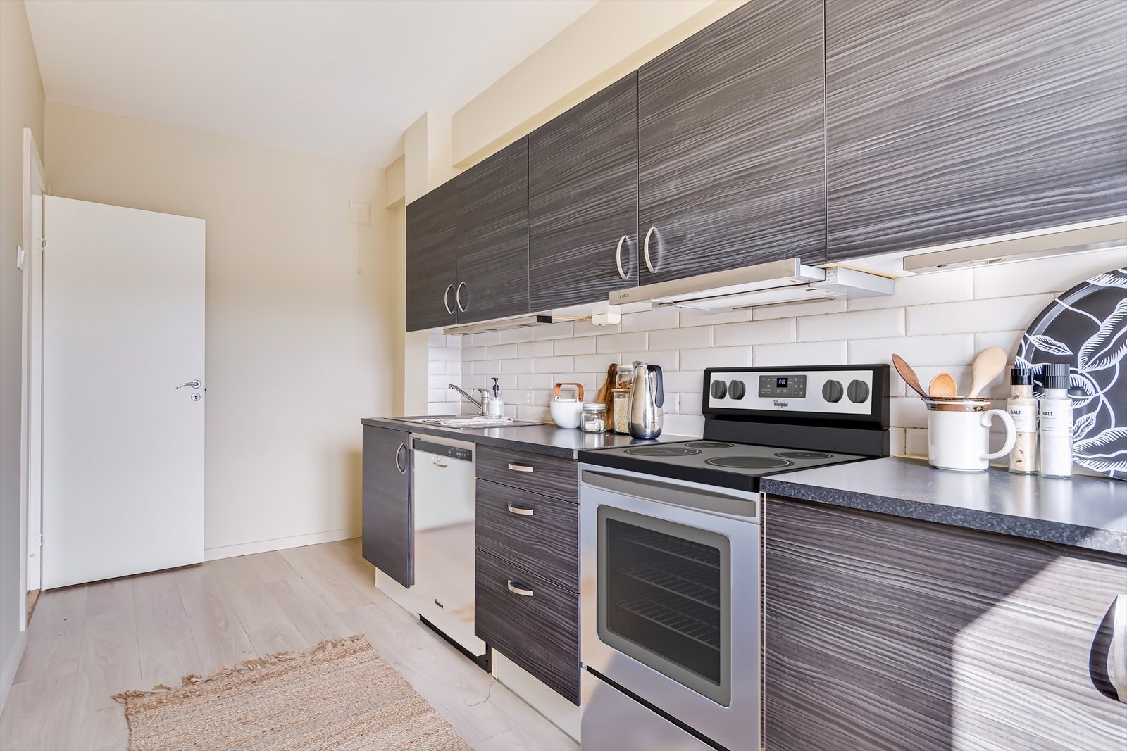 Kjøkkeninnredning med mørke, glatte fronter og benkeplate av laminat. Galleribilde