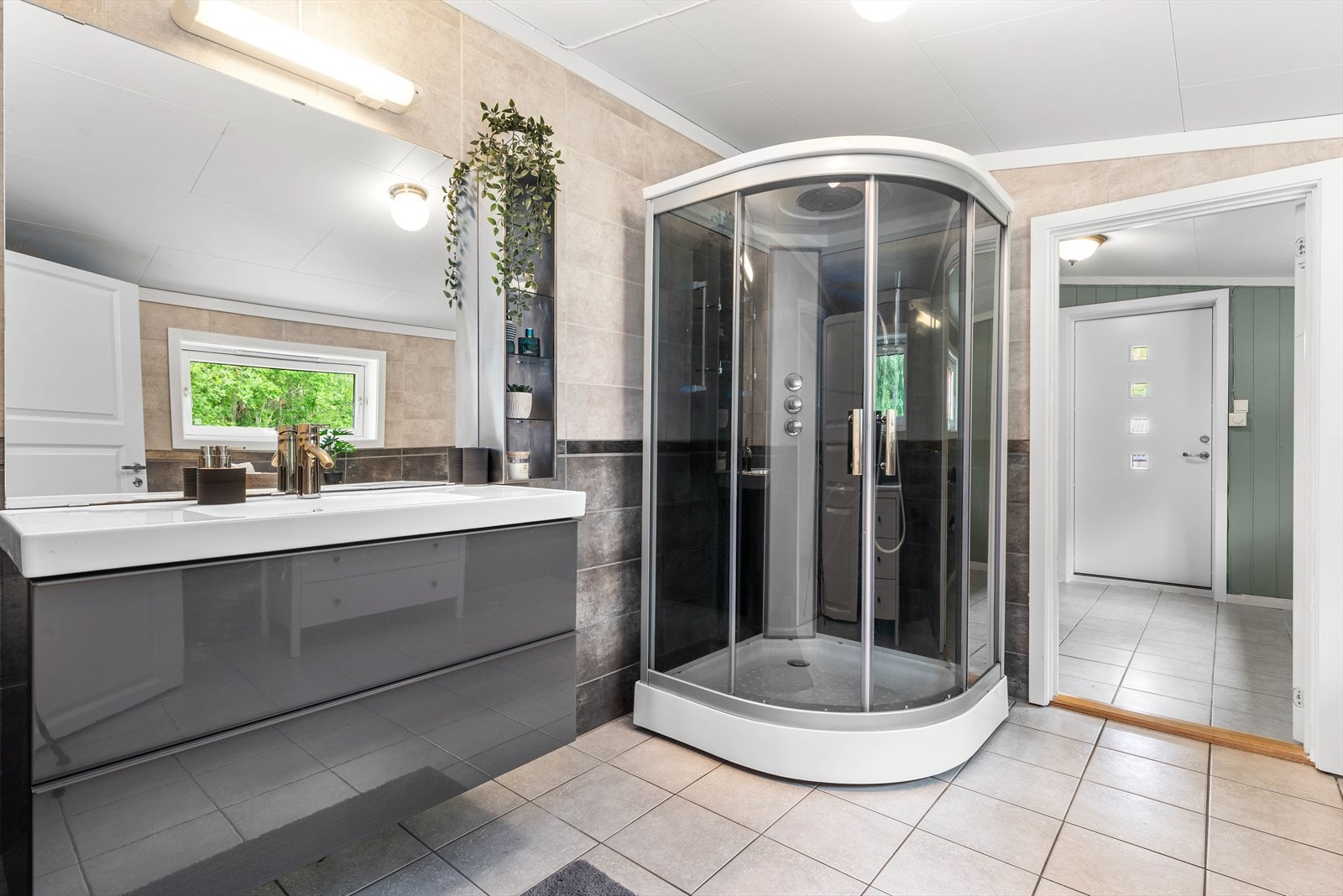 Badet er utstyrt med dusjkabinett, servant og servantskap. I tillegg er det behagelig gulvvarme på badet Galleribilde