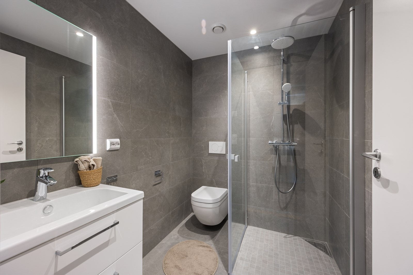 Delikat, flislagt baderom med varme i gulvet. Baderommet har innredning med nedfelt servant, veggmontert toalett og dusjvegger/hjørne. Det er balansert ventilasjon. Galleribilde