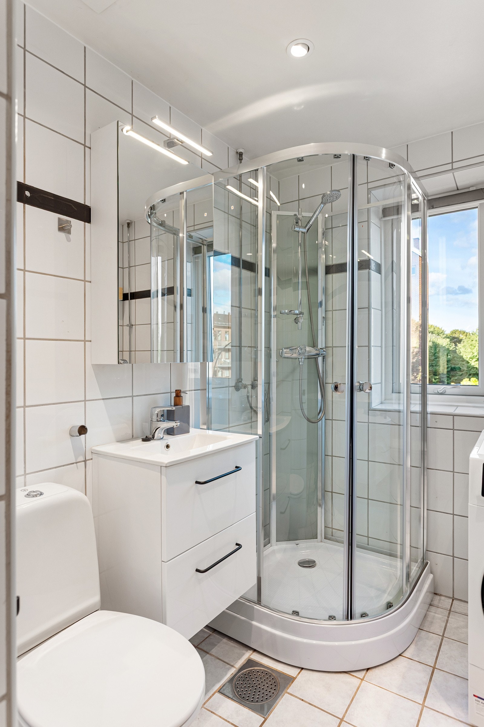 Dusjkabinett, servantskap med speilskap og belysning over, wc og opplegg for vaskemaskin. Galleribilde