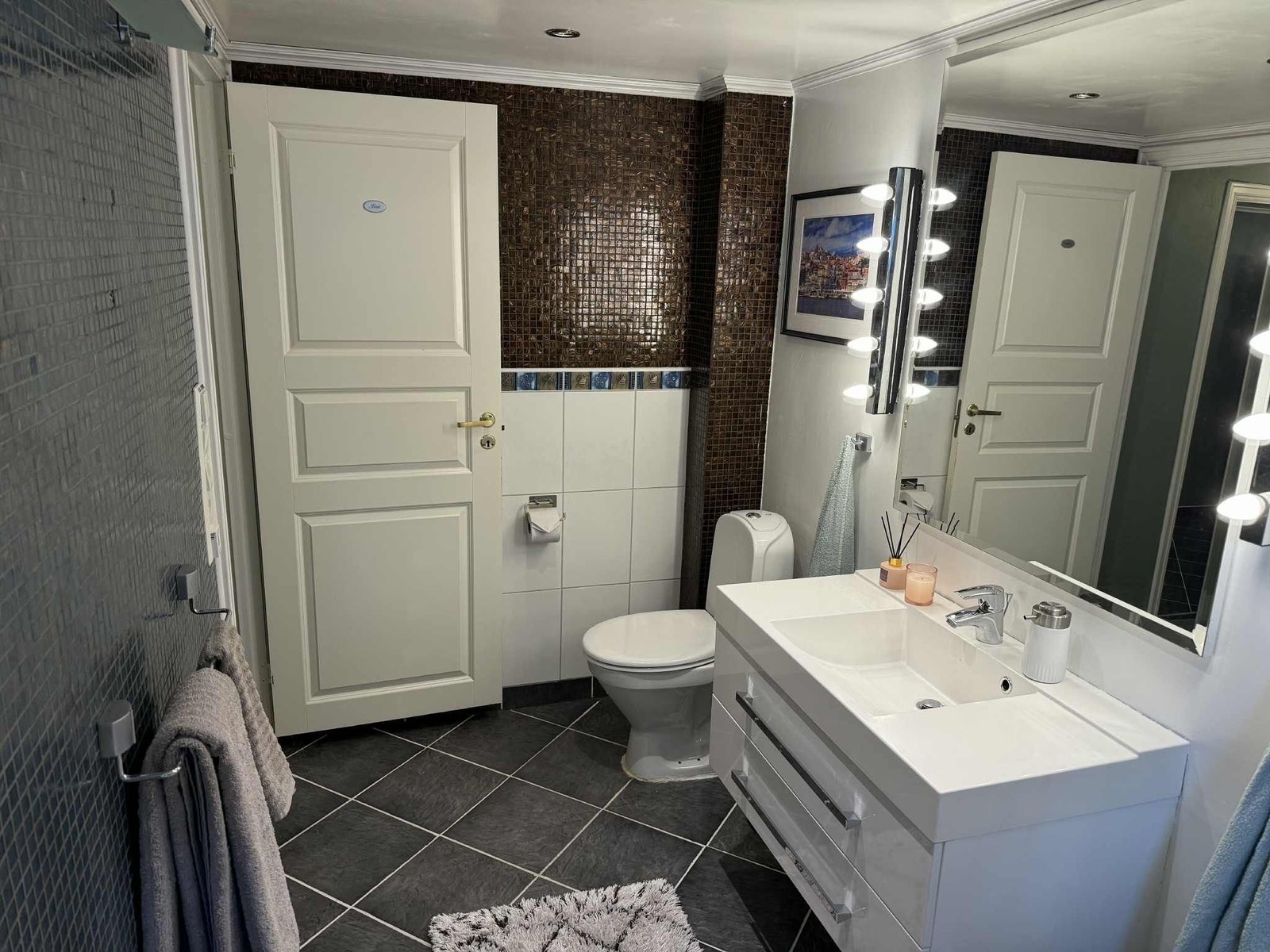 Stilrent bad med moderne innredning, god belysning og flislagte overflater som gir et tidløst uttrykk. Galleribilde