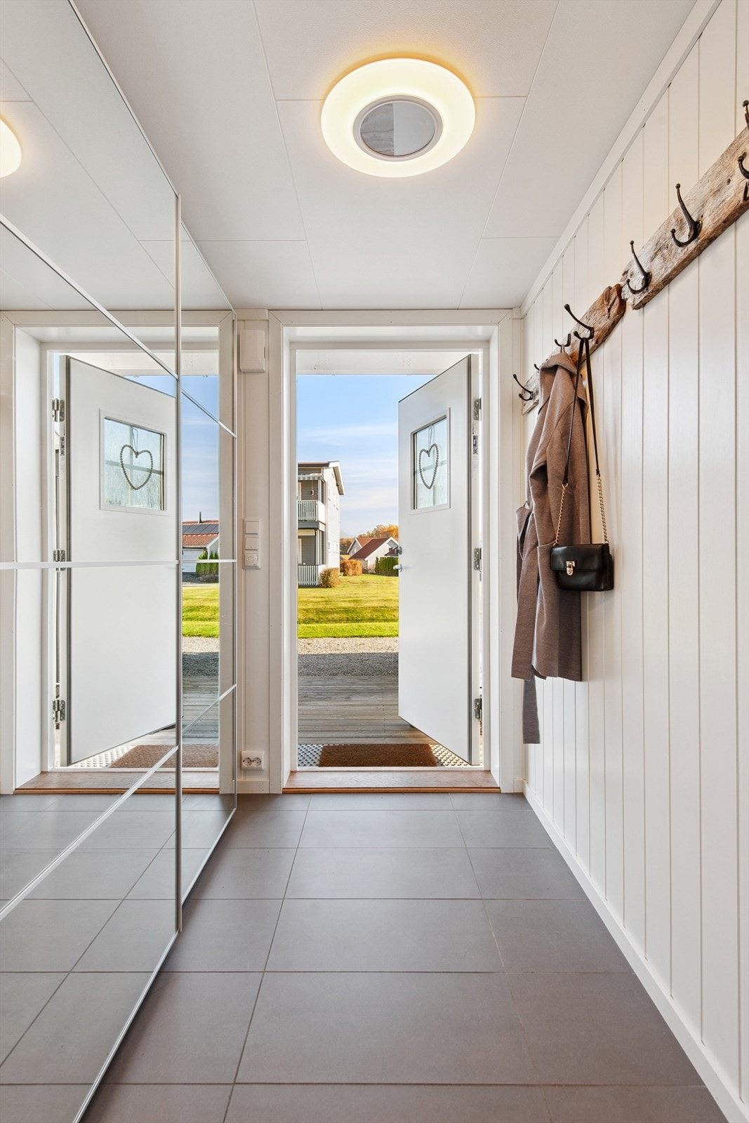 Velkommen inn i en lys entré med flislagt gulv med varmekabler, skyvedørsgarderobe og plass til yttertøy. Galleribilde