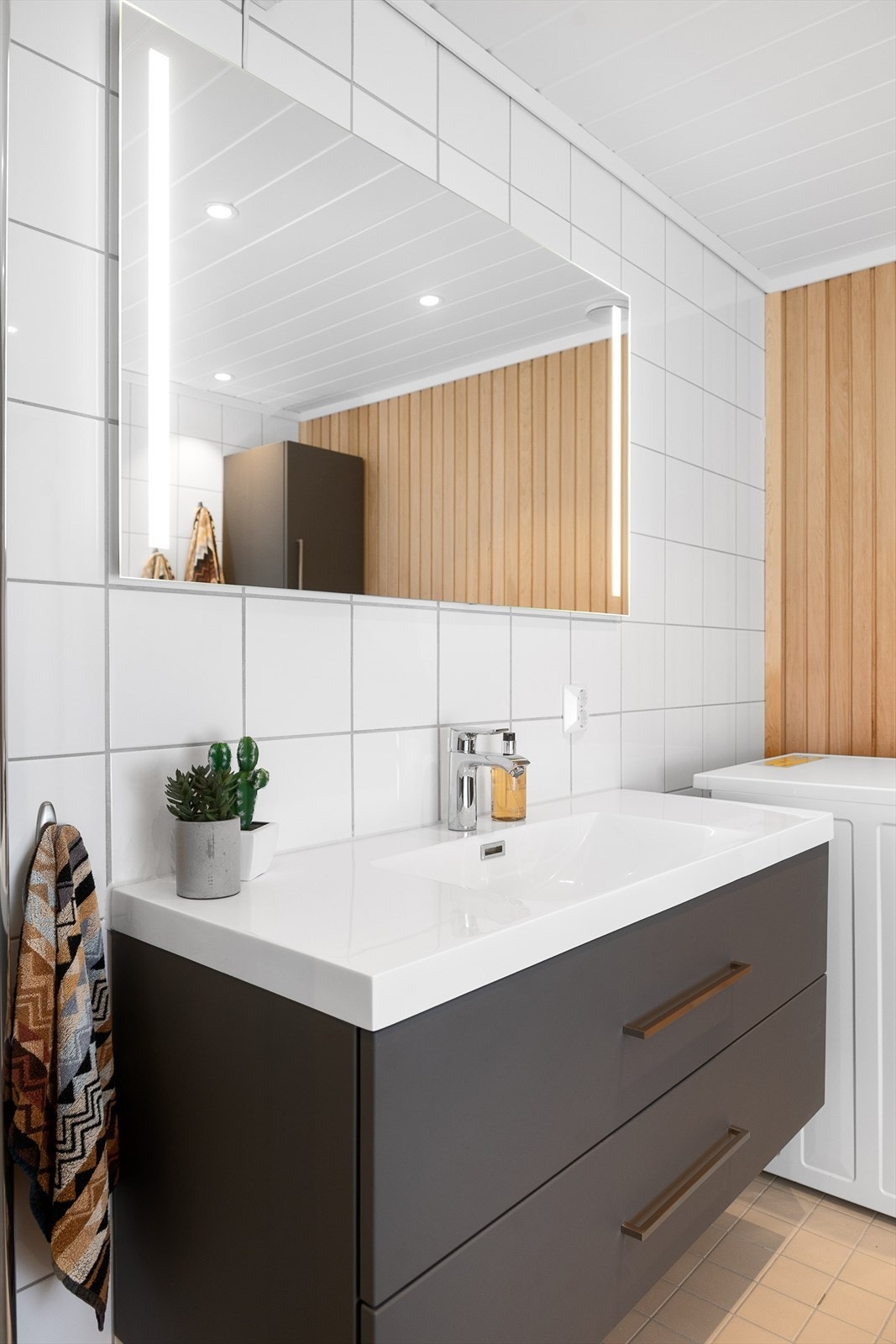 Badet har større baderomsinnredning, vegghengt toalett, dusjvegger og opplegg for vaskemaskin Galleribilde