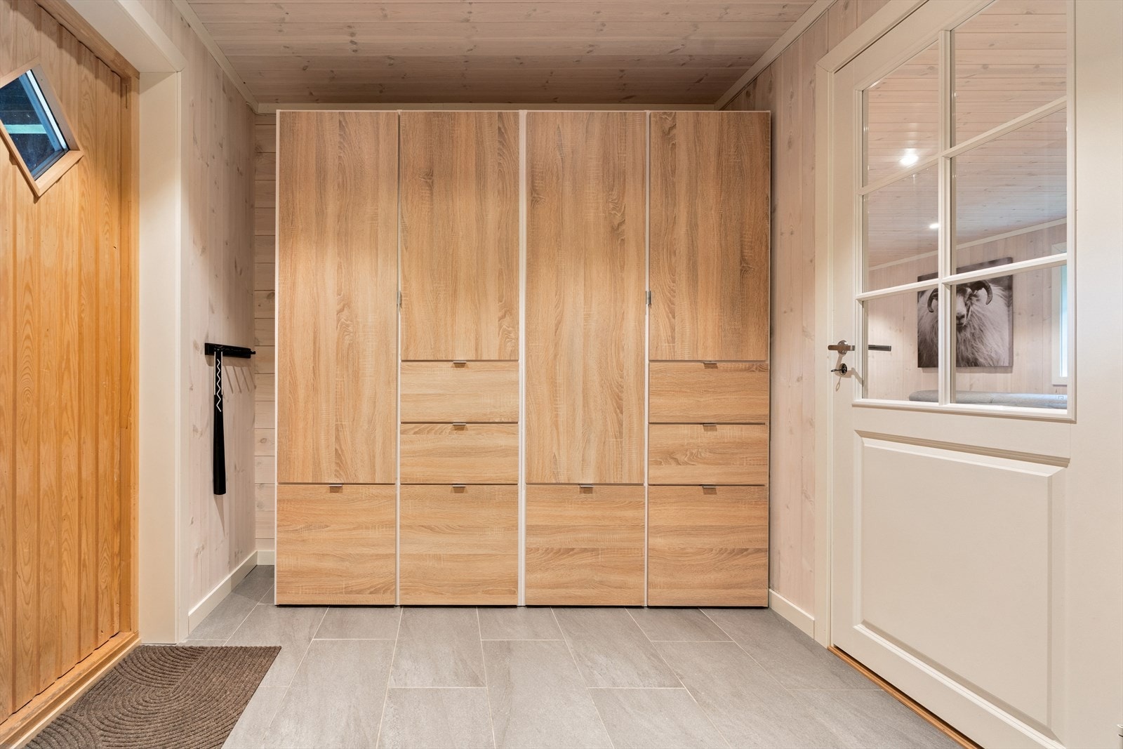 Velkommen inn. Flislagt golv med varmekablar og panel på veggar Galleribilde