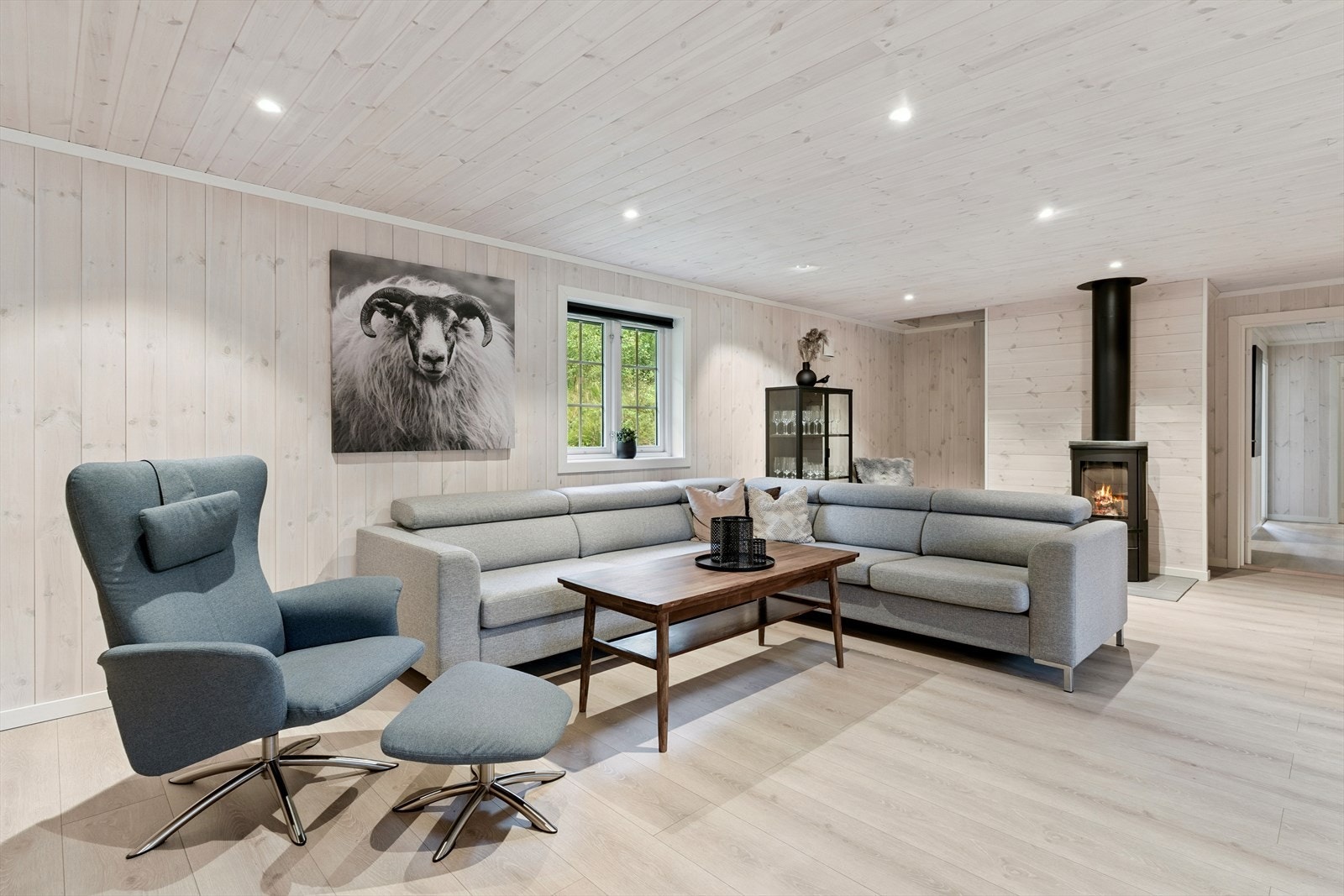 Vidare innover kjem du til ei meget lys og trivelig stove med laminat på golv og lyst panel på veggar. Her ligg det varmefolie i golvet. Galleribilde