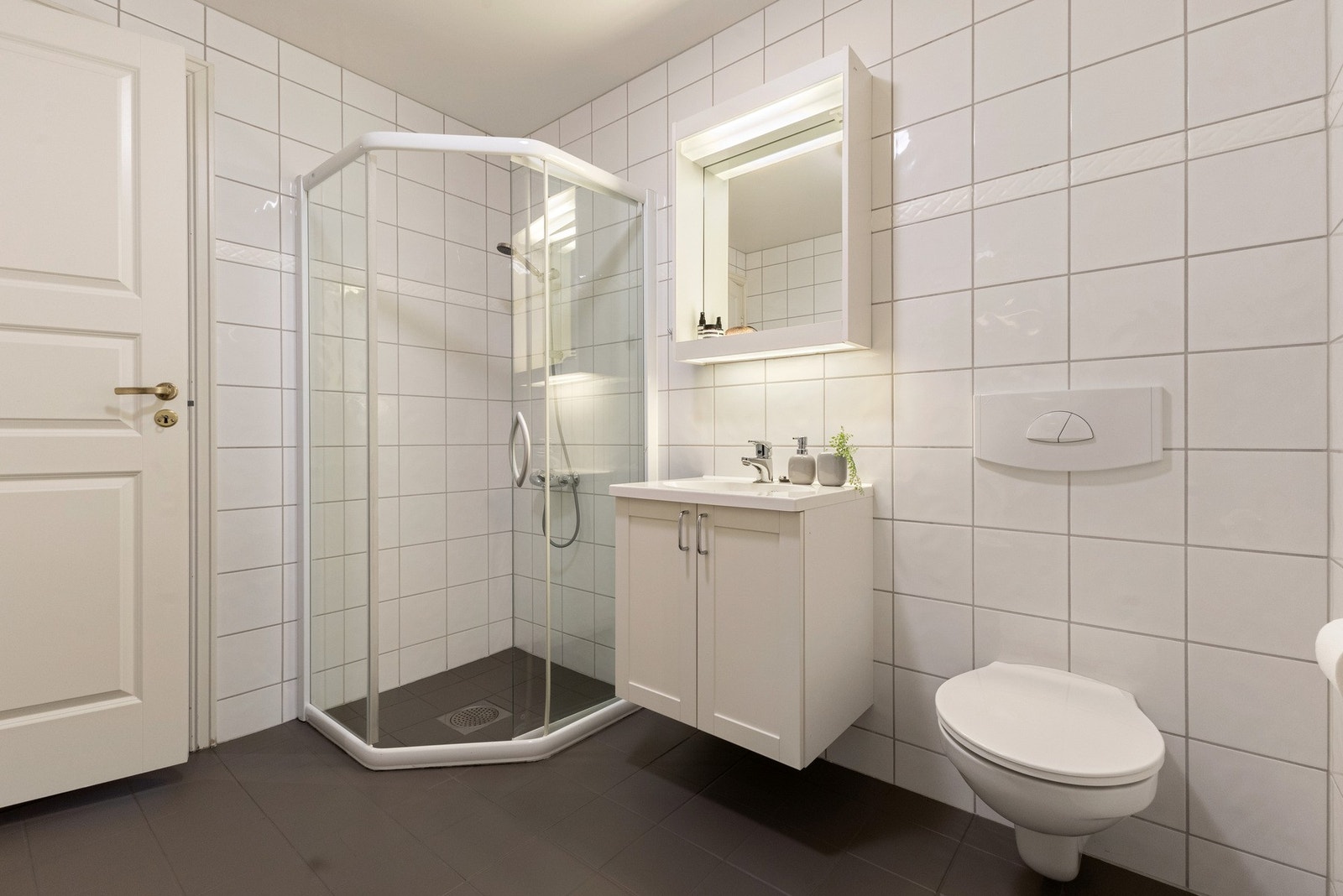 Badet har vegghengt servantinnredning med skapplass og speil med belysning på vegg. Galleribilde