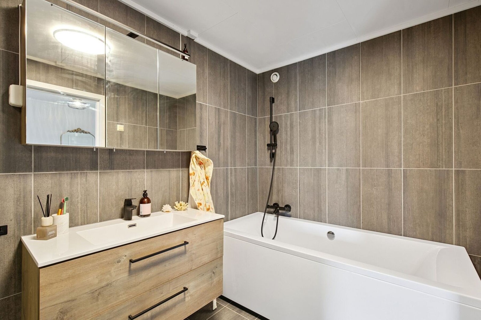 Romslig, flislagt baderom på hele 6 kvadratmeter med god arealutnyttelse innredet med badekar, dusjkabinett og stor servant. Galleribilde