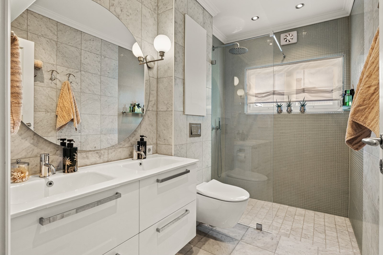 Nytt bad fra 2020 med Carrara marmor, glassmosaikk i dusjsonen, innredning med dobbel vask og design-armaturer fra Vola Galleribilde