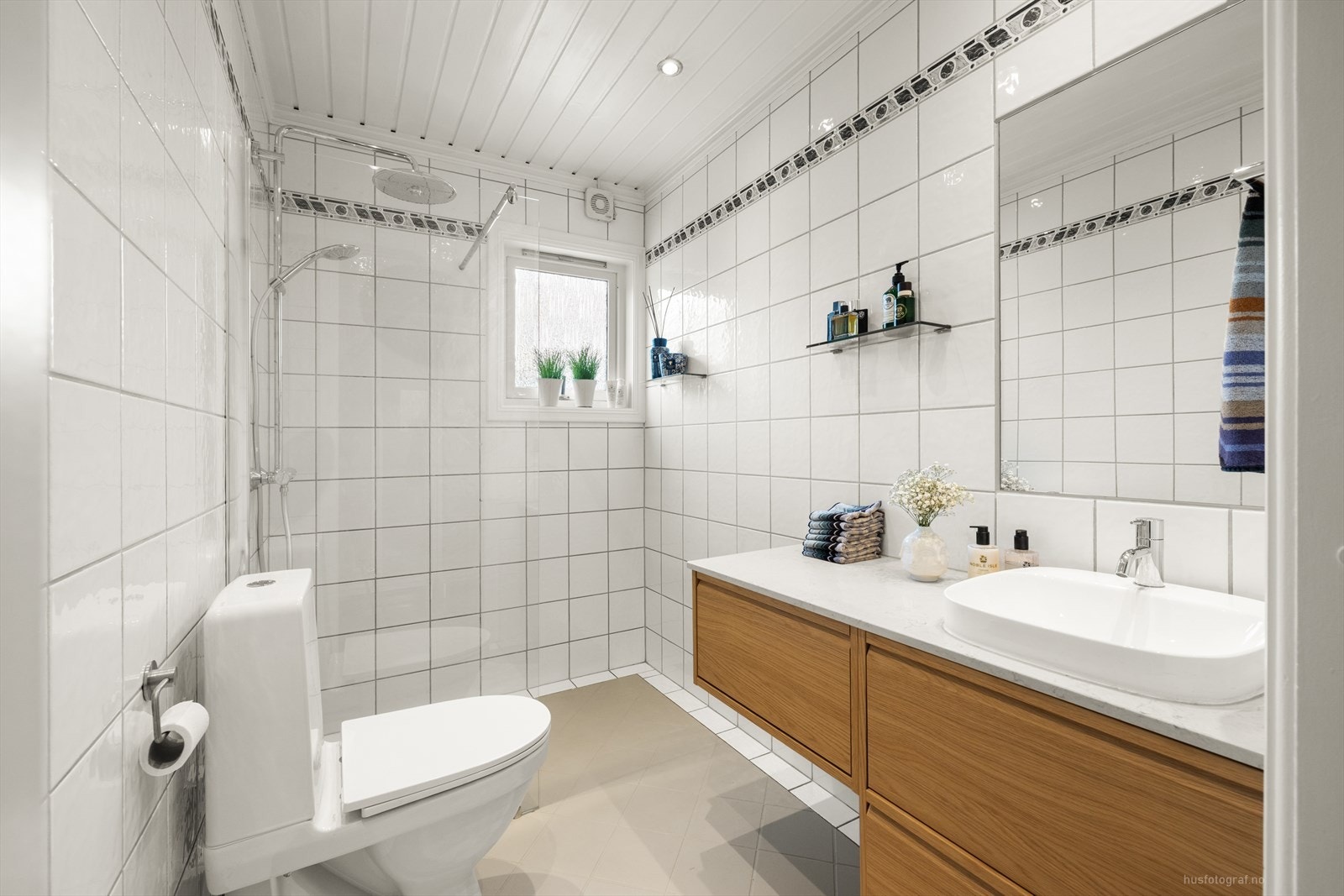 Flislagt bad med ny og lekker baderomsinnredning tidsriktig steinplate. Armatur på vask fra eksklusive Vola. Galleribilde