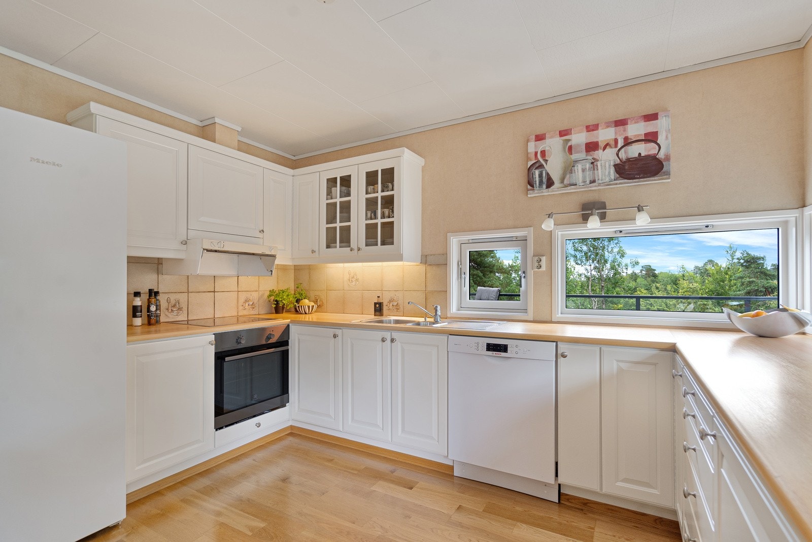 Pen og innholdsrik kjøkkeninnredning med frontert i lakkert heltre furu Galleribilde