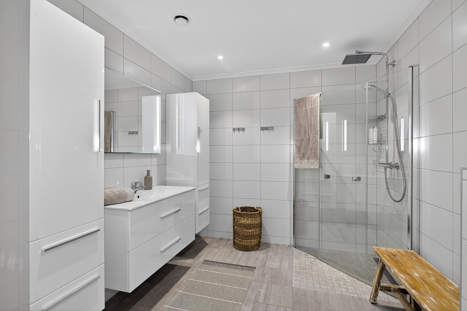 Delikat bad med flis på gulv og og vegger. Her er det vegghengt toalett, dusjhjørne med glassdører og innredning. Det er varmekabler i gulv og ventilasjon via ventilasjonsanlegg. Galleribilde