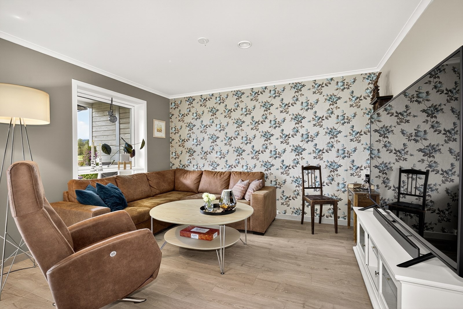 Stuen er lys og pen med store vindusflater som slipper godt med lys inn.
En del av stuen var opprinnelig tiltenkt et ekstra soverom, men dette er i dag en hyggelig sofa- og tv krok. Galleribilde