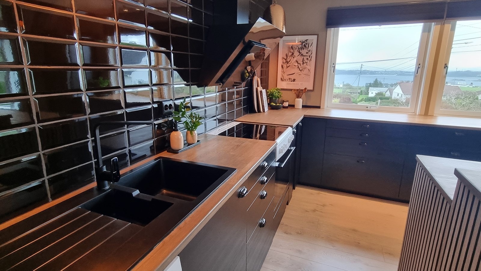 Kjøkkenet har innredning med svarte fronter og heltre benkeplate i eik - det er også montert spileplater som gir kjøkkenet et moderne uttrykk (selgers bilde) Galleribilde