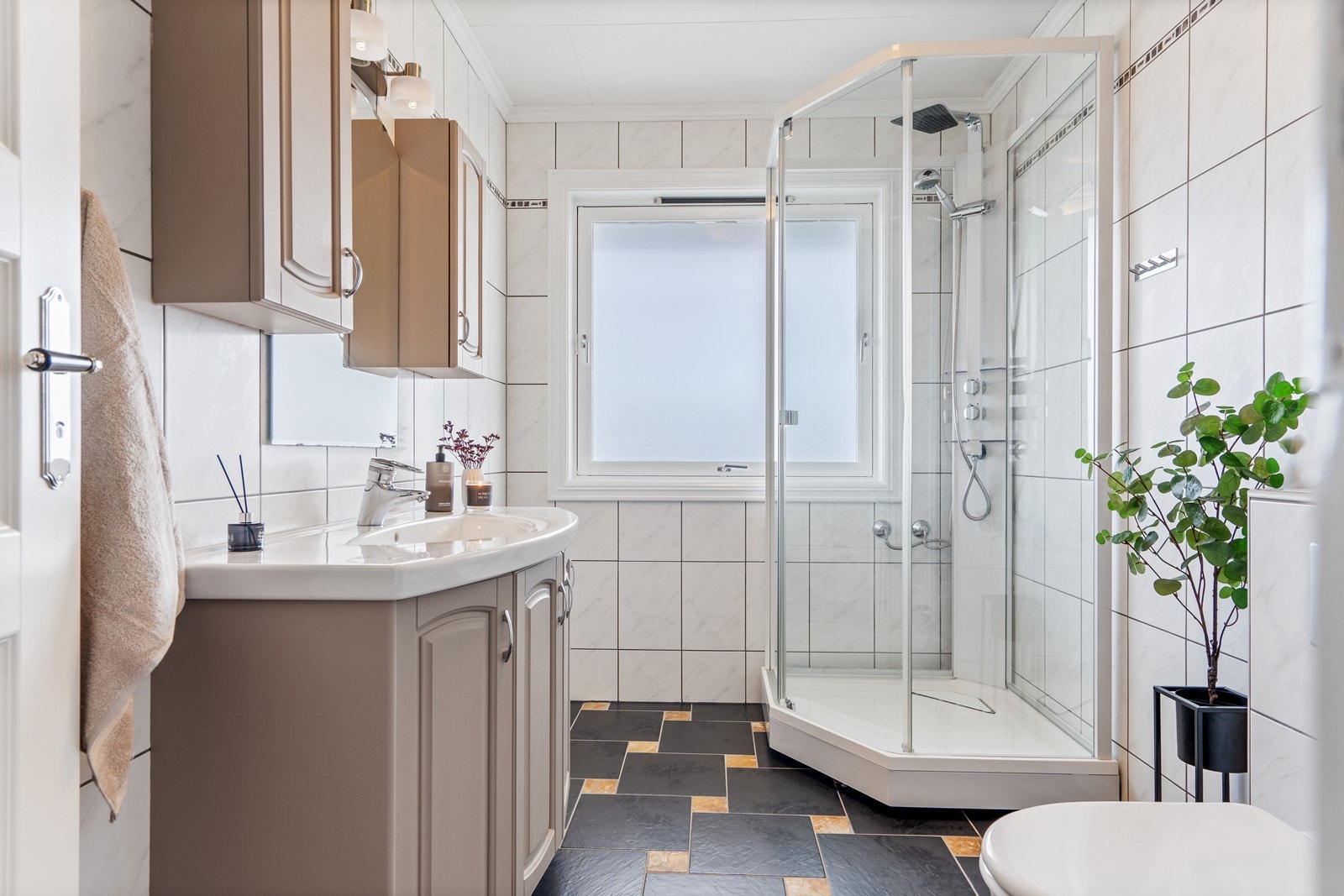 Boligen har et bad i hver etasje - badet i 1. etasje er helfliset og innredet med vegghengt toalett, dusjkabinett og pen baderomsinnredning Galleribilde