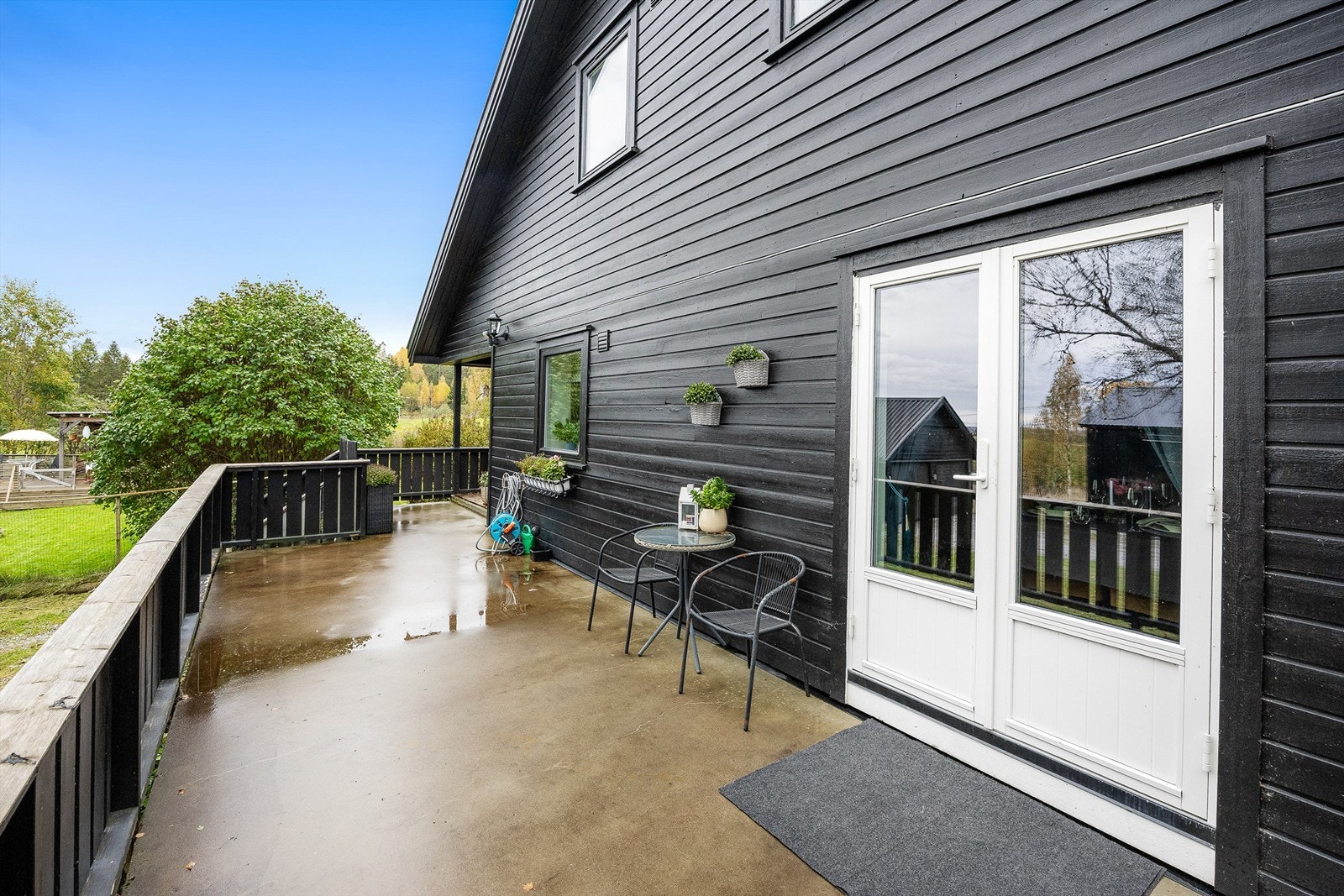 Terrassen strekker seg rundt fremsiden av boligen med adkomst fra stuen og inngangspartiet. Galleribilde