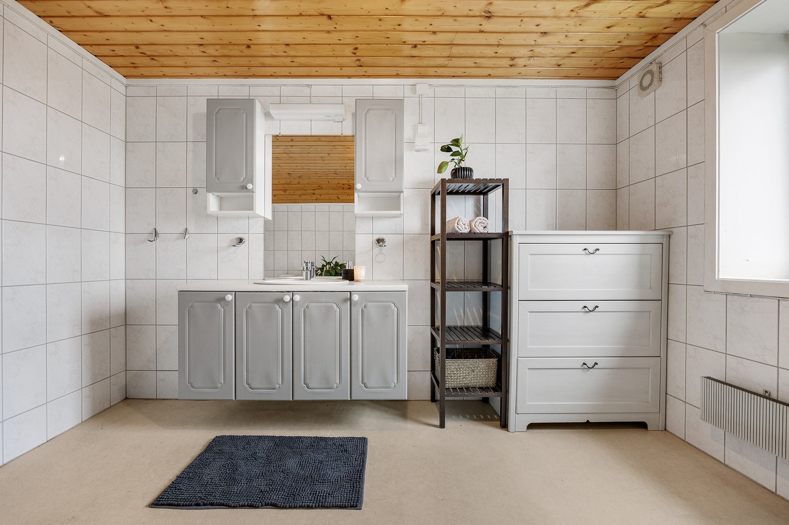 Baderomsinnredningen består av benkeskap og veggskap med profilerte fronter og speil over servant. Gulvstående WC og dusjing i dusjkabinett. Galleribilde