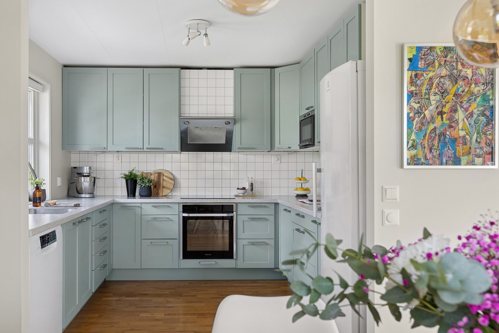 Innredningen er fra 2005 med malte fronter (malt i 2025), laminat benkeplate og utslagsvask med ett-greps blandebatteri. Galleribilde