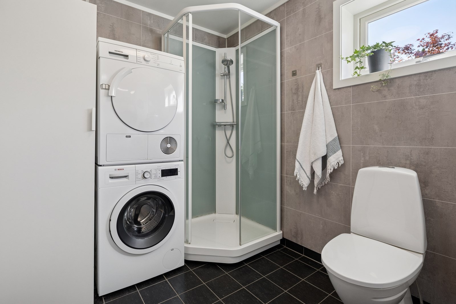 Badet er utstyrt med toalett, dusjkabinett, baderomsinnredning med servant, samt opplegg for vaskemaskin og tørketrommel. Galleribilde