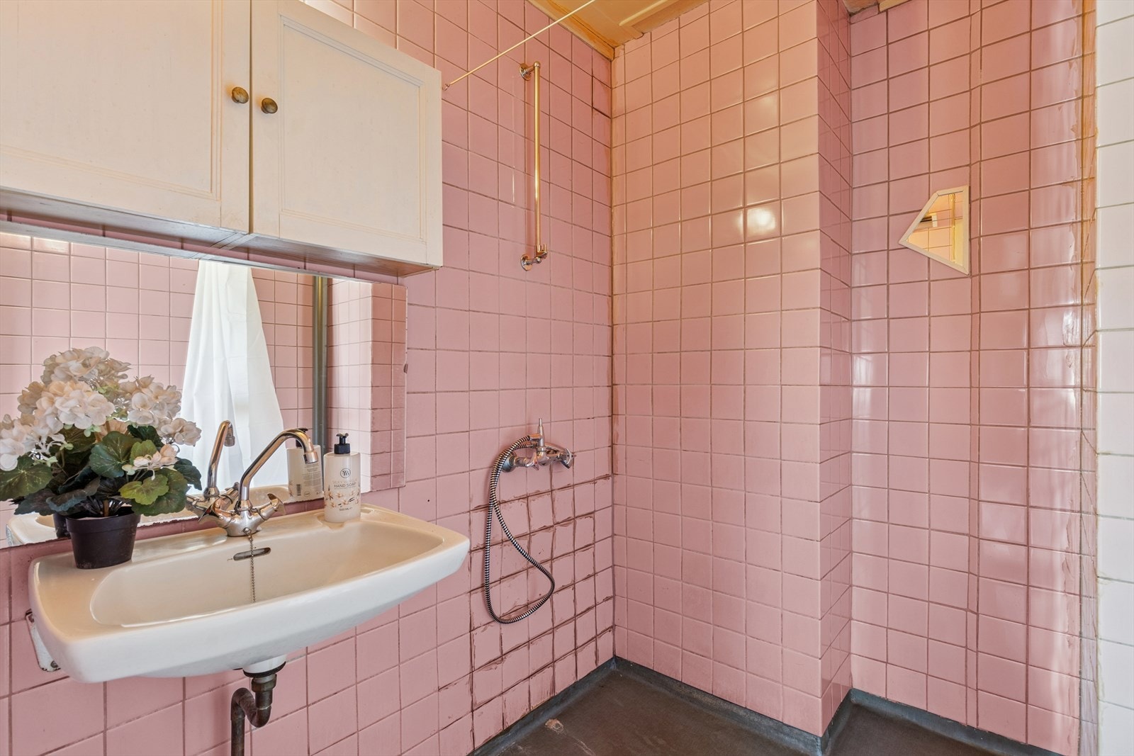 Bad med renoveringsbehov. Badet er utstyrt med dusjhjørne og enkel servant på vegg. Galleribilde