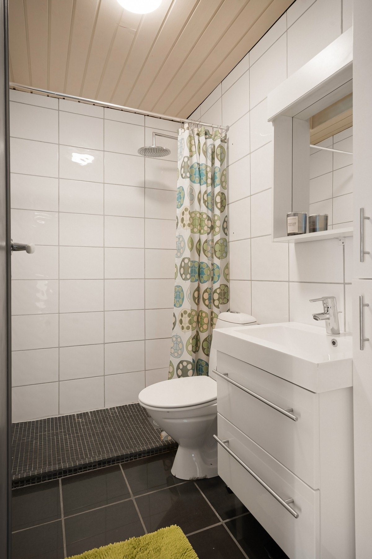 Flislagt bad med dusj, gulvstående toalett og servant på innredning. Varme i gulv Galleribilde