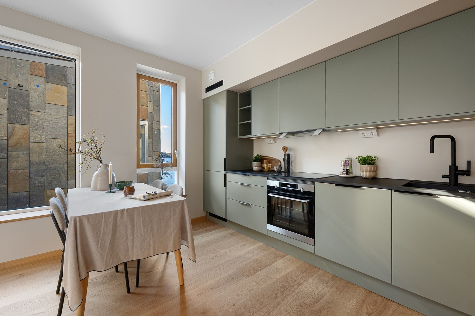 Integrert i innredning er kjøl/frys, oppvaskmaskin, komfyr og platetopp. Belysning mellom overskap og benk. Galleribilde