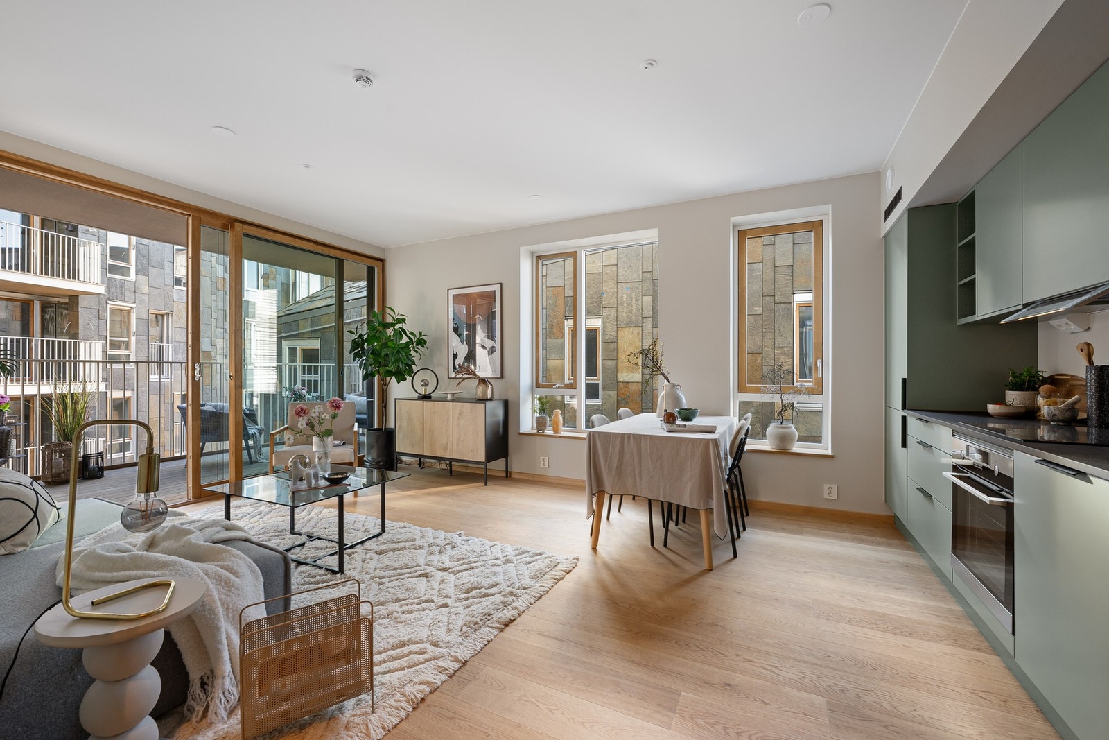 Lys og moderne stue kombinert med åpen kjøkkenløsning. Lekker én-stavs eikeparkett og slette veggflater. Galleribilde