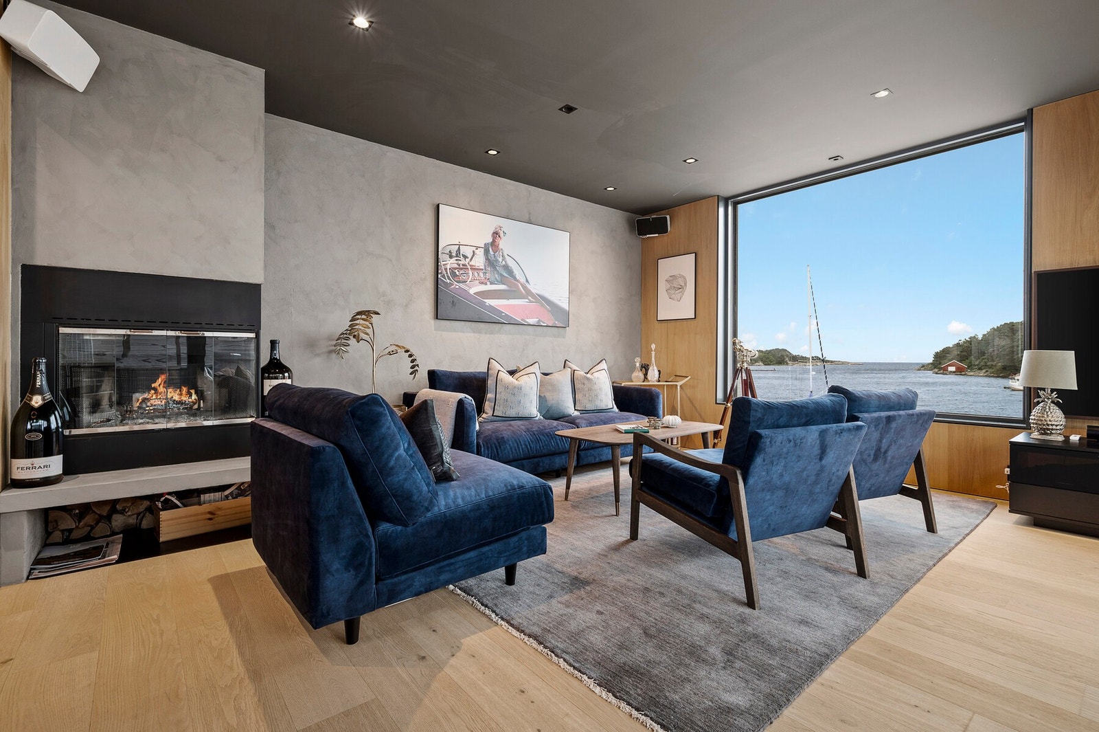 Eksklusivt interiør med peis, varme naturmaterialer og store vinduer som rammer inn sjøutsikten. Galleribilde