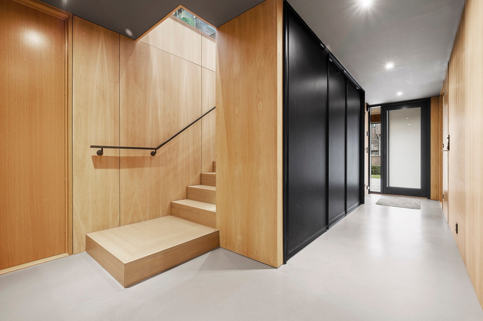 Lys og moderne hall med integrert garderobeløsning og en stilren trapp som elegant leder deg opp til boligens sosiale sone. Galleribilde