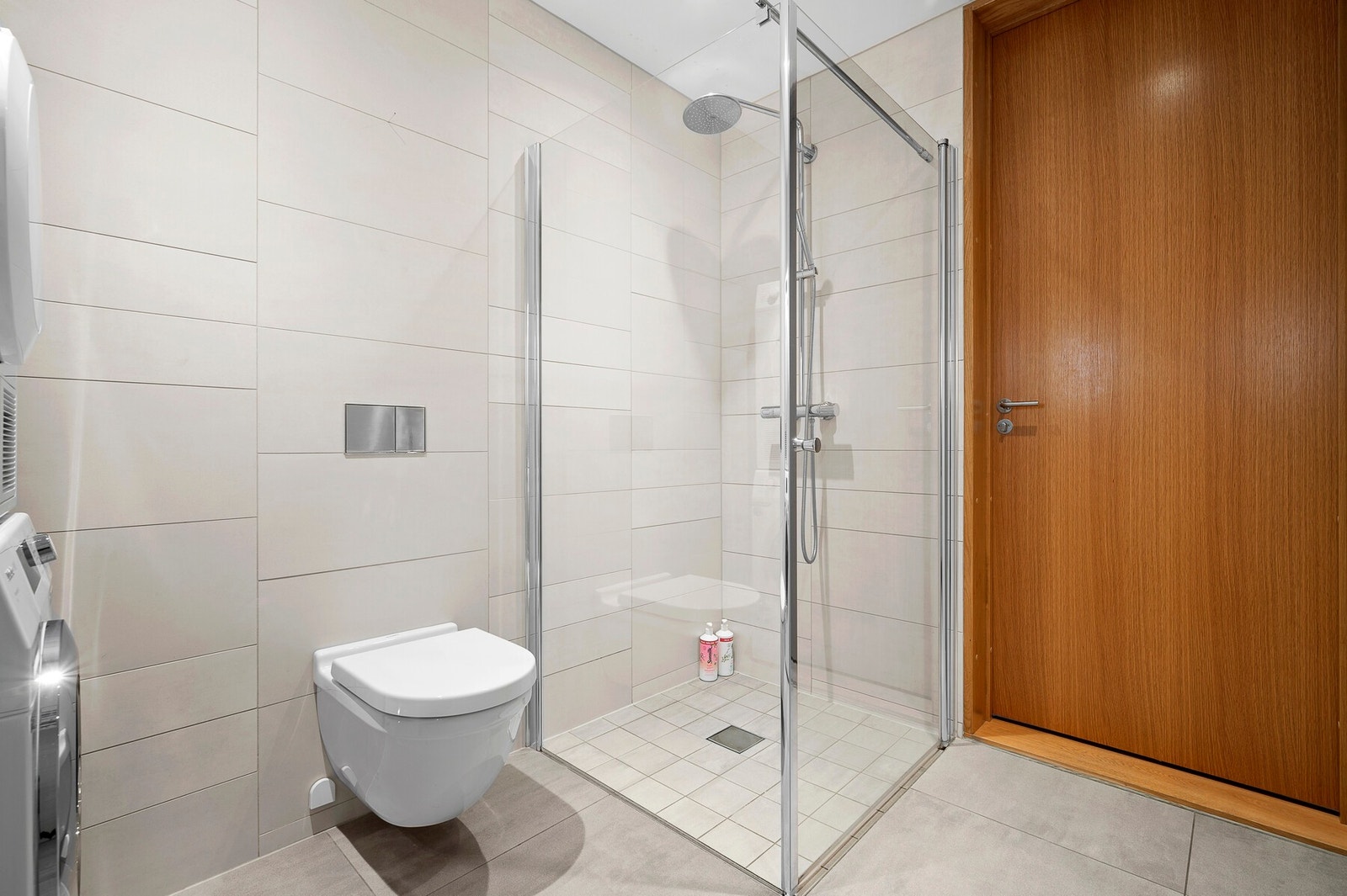 Romslig hovedbad med dusjhjørne, vegghengt toalett og delikate fliser - et lyst og elegant rom med gjennomførte kvaliteter. Galleribilde