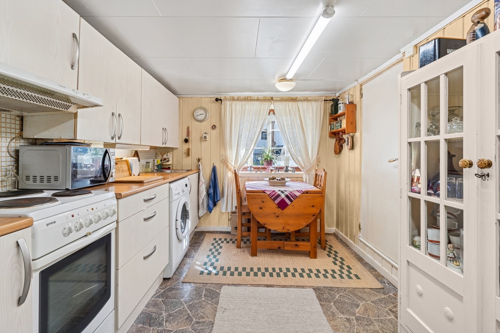 Slett hvit kjøkkeninnredning med opplegg for vaskemaskin Galleribilde