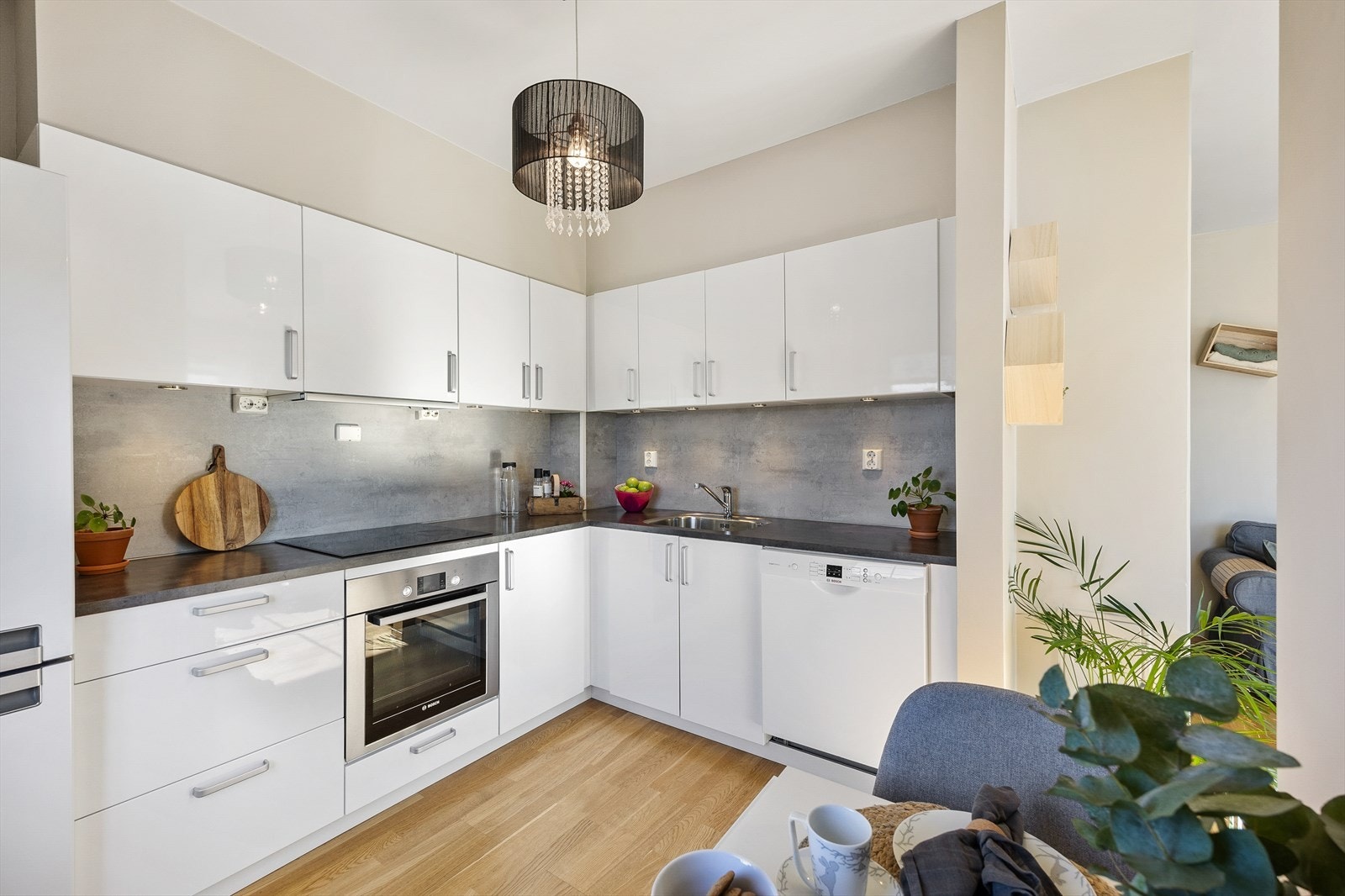 Kjøkkenet har en praktisk hjørneløsning med glatte, hvite fronter og integrerte hvitevarer. Galleribilde