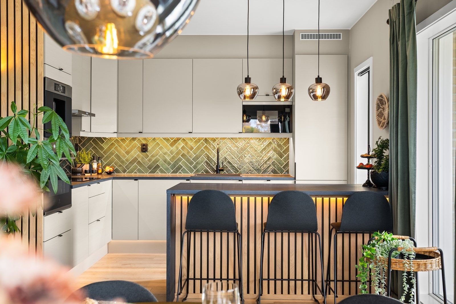 Detaljer som takhøye overskap og en svært praktisk kjøkkenøy. Øyen fungerer som et naturlig skille mot stue og har både vinskap, ledlys og spiledetaljer. Galleribilde