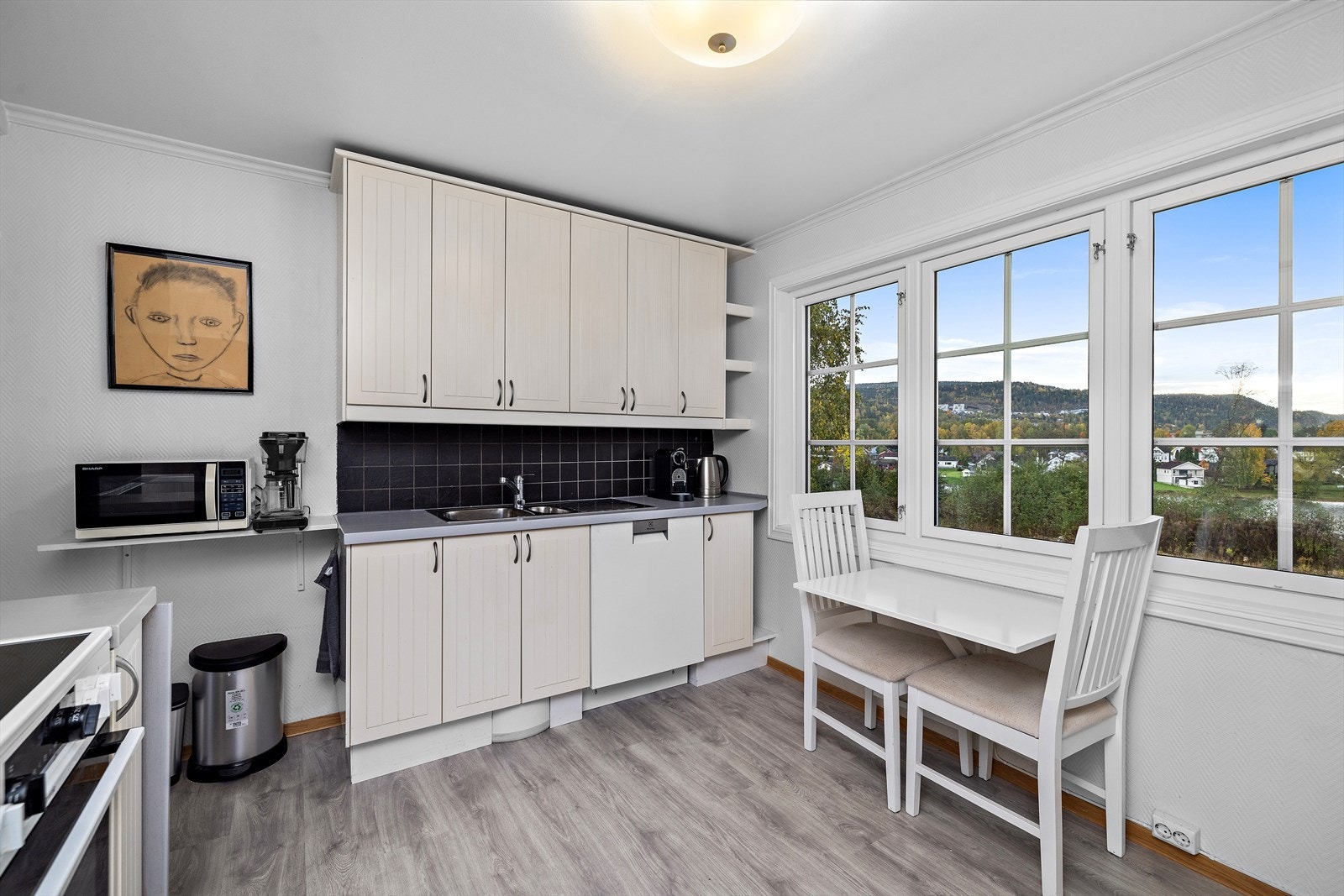 Kjøkkenet har en behandlet innredning med profilerte fronter, samt en benkeplate i heltre som er malt og utstyrt med nedfelt oppvaskkum. Galleribilde