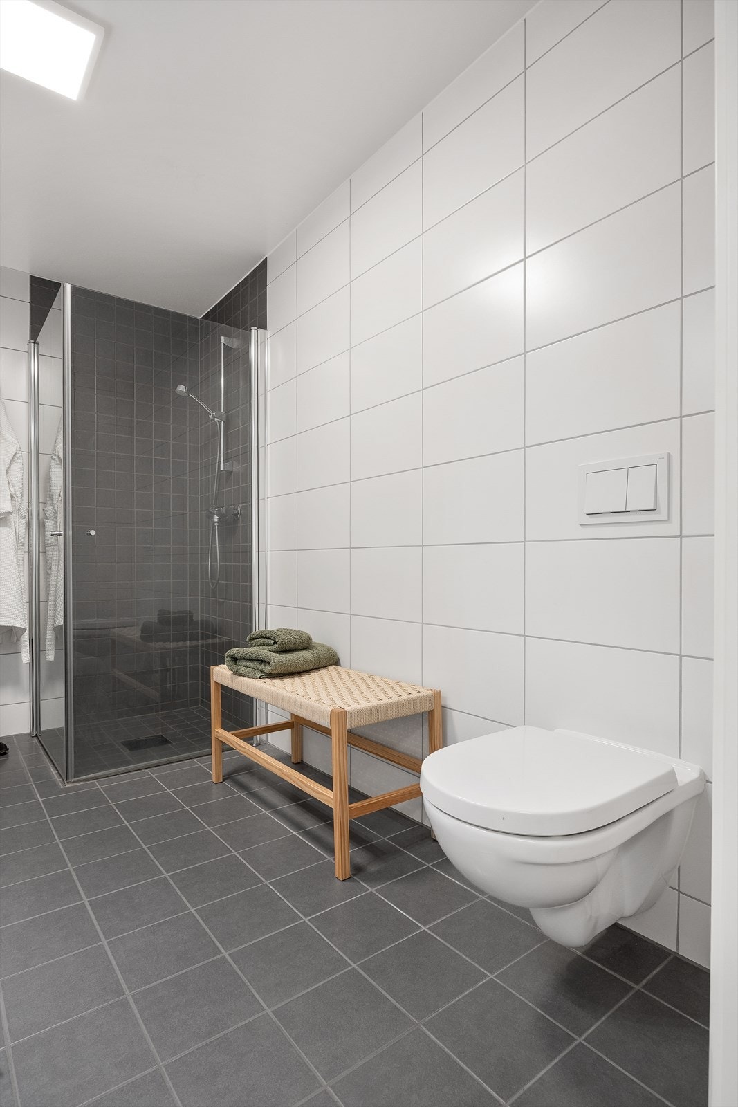 Badet har innredning med nedfelt servant, veggmontert toalett, dusjhjørne og opplegg for vaskemaskin. Galleribilde