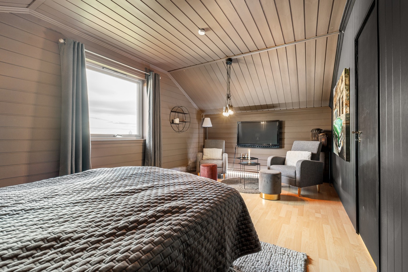 Innredet med dobbeltseng, TV og koselig sittehjørne med to stoler Galleribilde