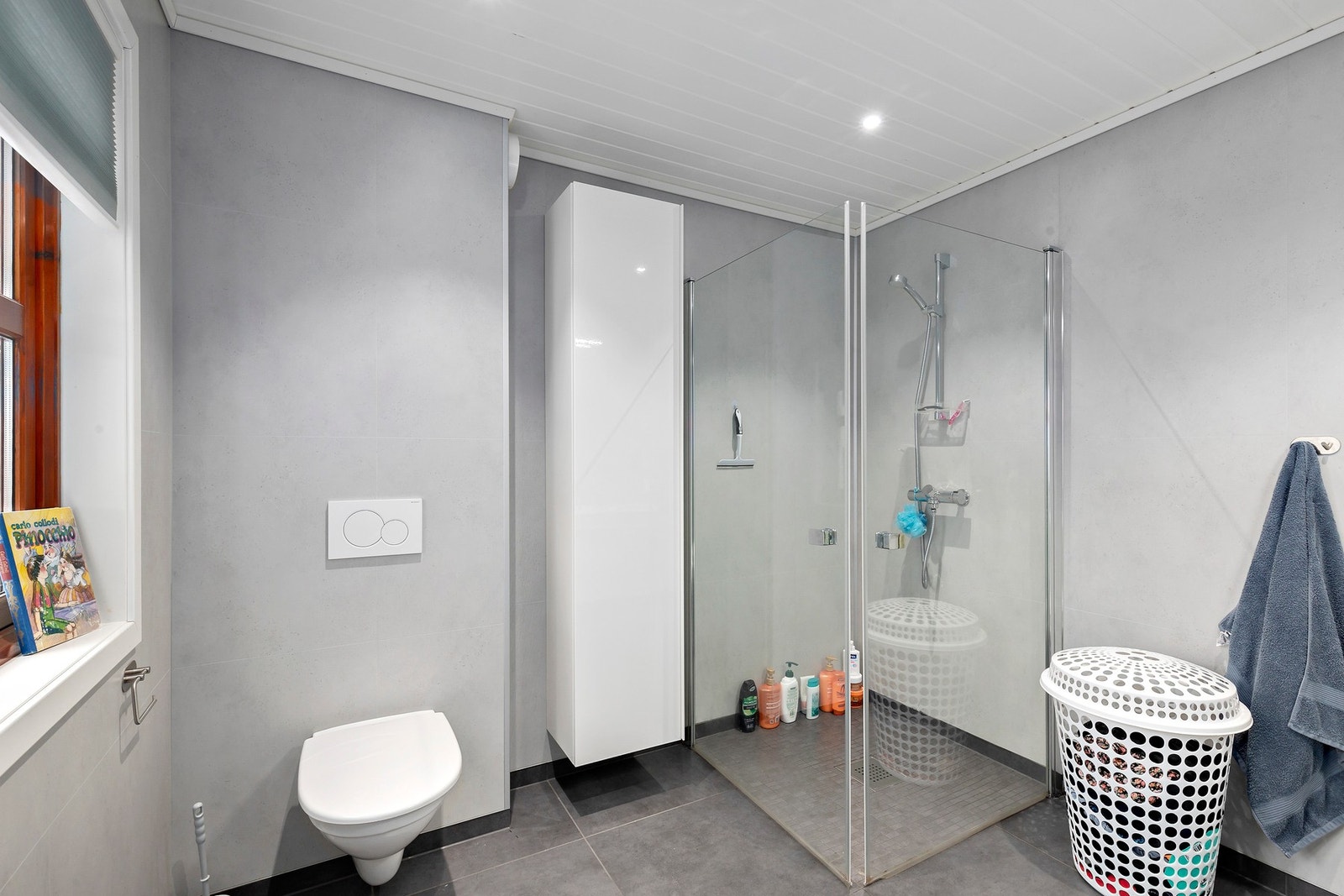 Badet er utstyrt med innfellbare dusjdører, veggmontert WC, servant og servantskap. Galleribilde