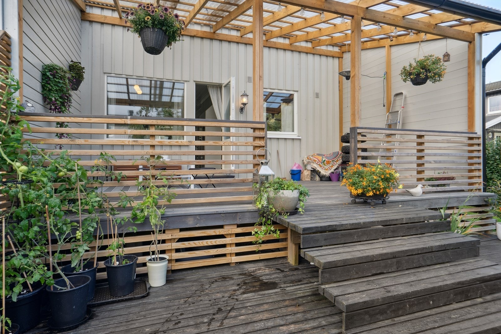 På den takoverbygde terrassen sitter man lunt og godt. Ved ønske om mer sol kan man trekke ut på plattingen nedenfor. Galleribilde