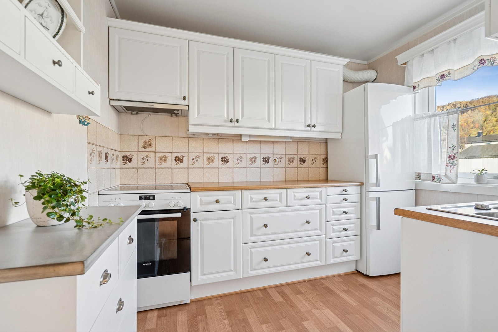 Kjøkkenet er innredet med profilerte fronter, og fliser på vegg over benkeplaten. Galleribilde