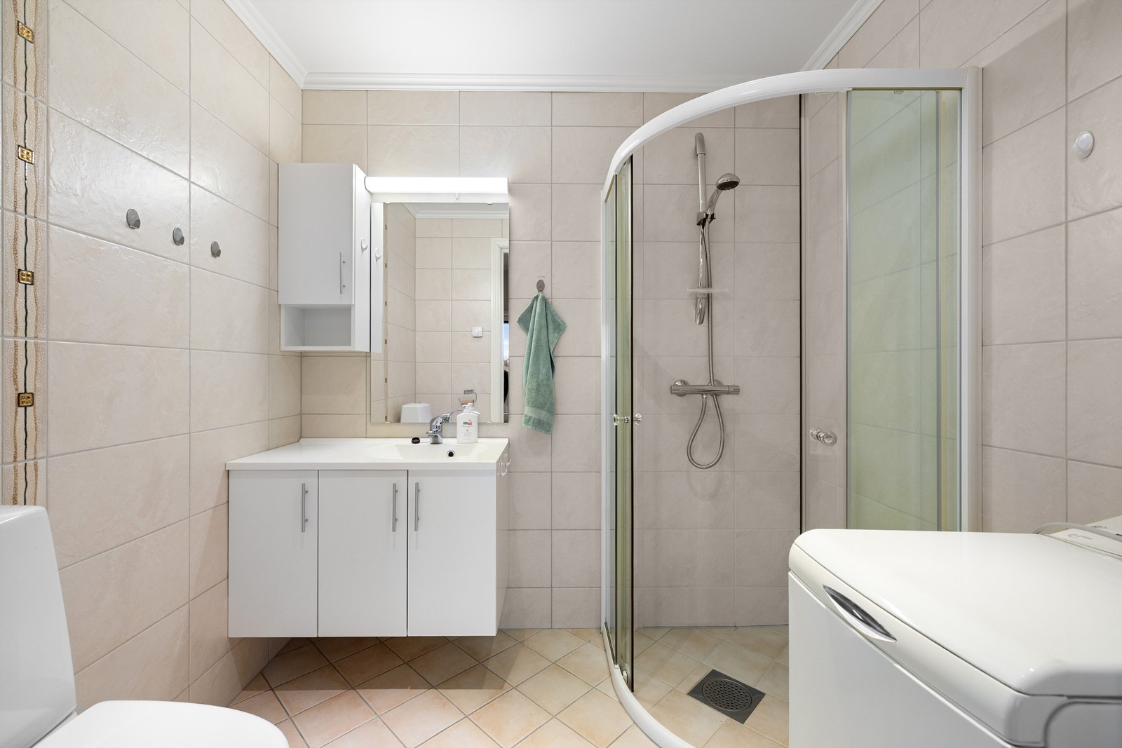 Lyse fliser på gulv og vegger gir badet helhet. Baderomsinnredningen og sanitærutstyret for øvrig er fra 2009 og i god stand. Galleribilde