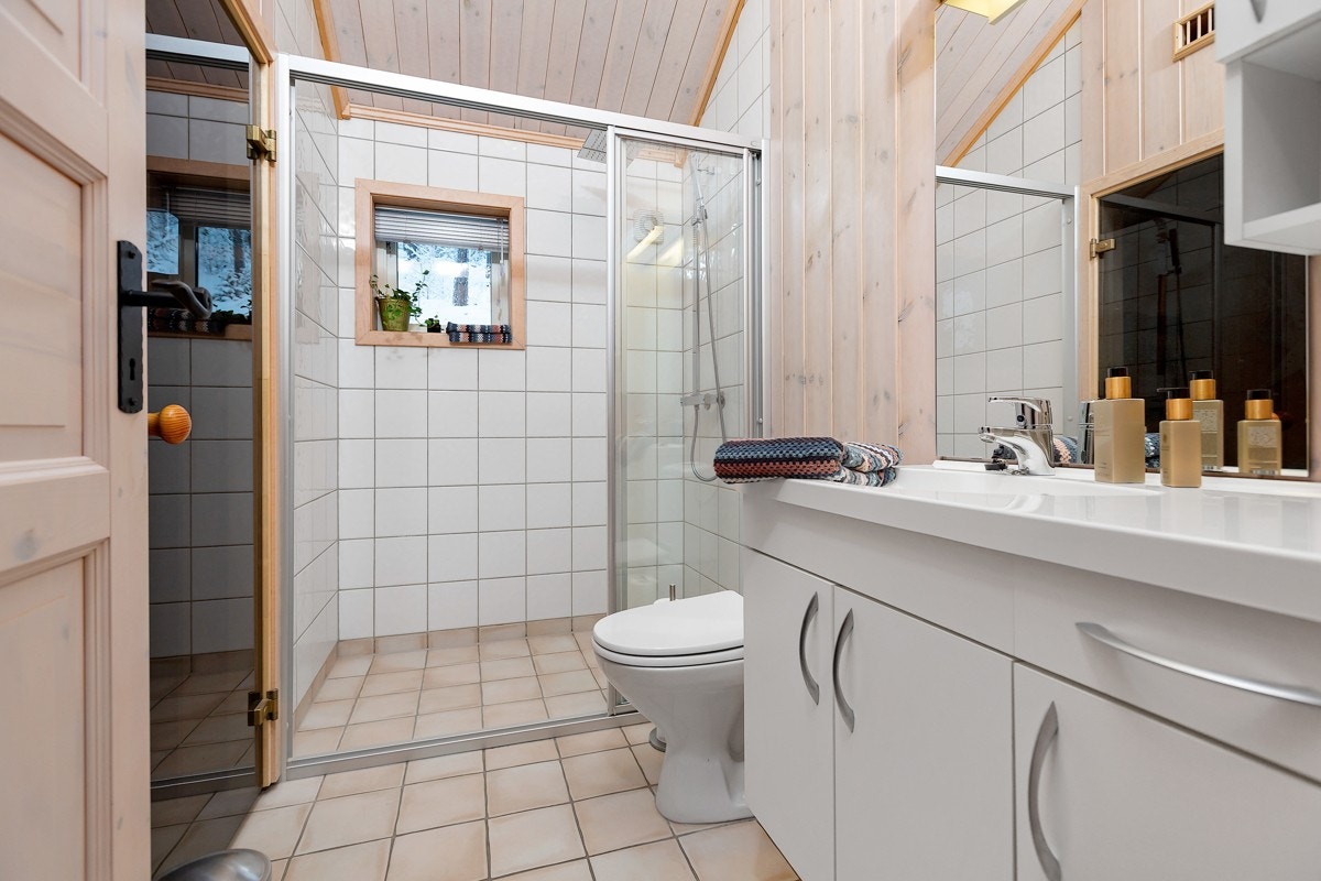 Bad 2 er innredet med et gulvmontert toalett, servantskap med heldekkende servantplate med ettgreps armatur og dusjvegger i glass. Galleribilde