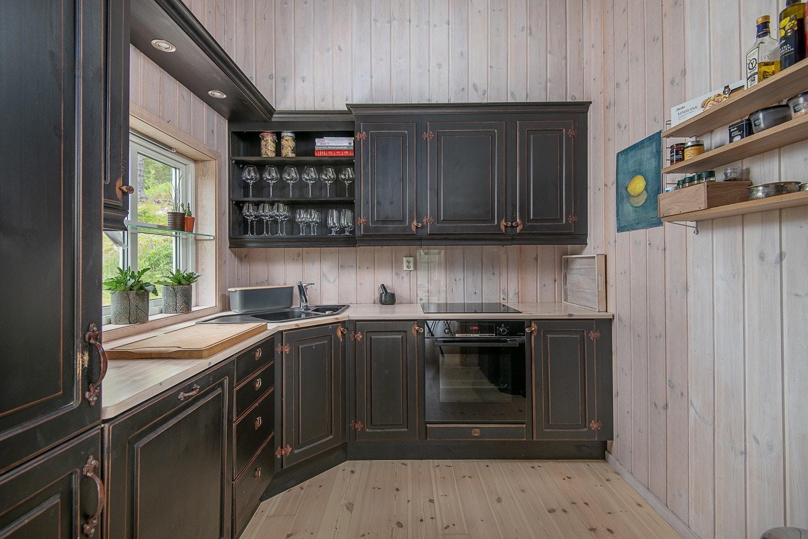 Kjøkkenet har innredning i heltre med mørke, profilerte fronter, benkeplate i heltre, og glassfelt i enkelte overskap. Integrerte hvitevarer. Galleribilde