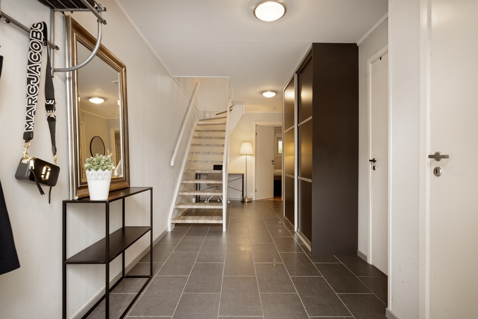 Romslig entré med flislagt gulv, varmekabler og skyvedørsgarderobe Galleribilde