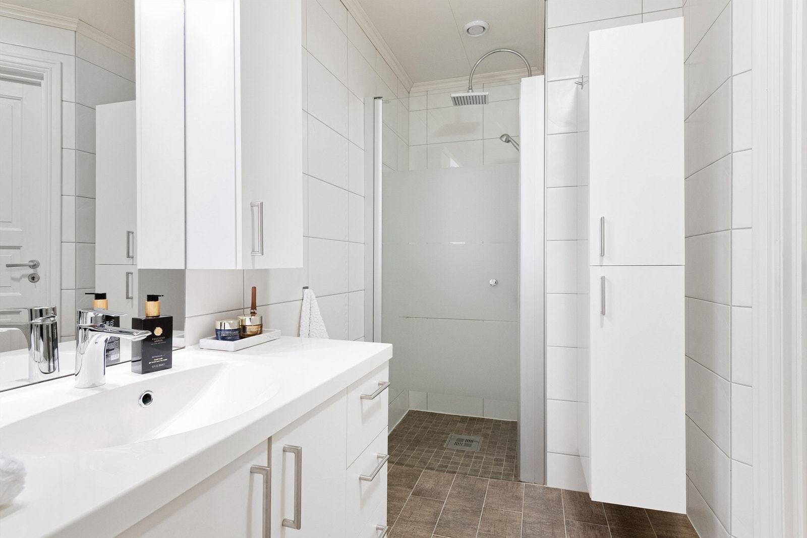 Dusjnisje på bad med glassdør. Vegghengt skap med gode oppbevaringsmuligheter Galleribilde