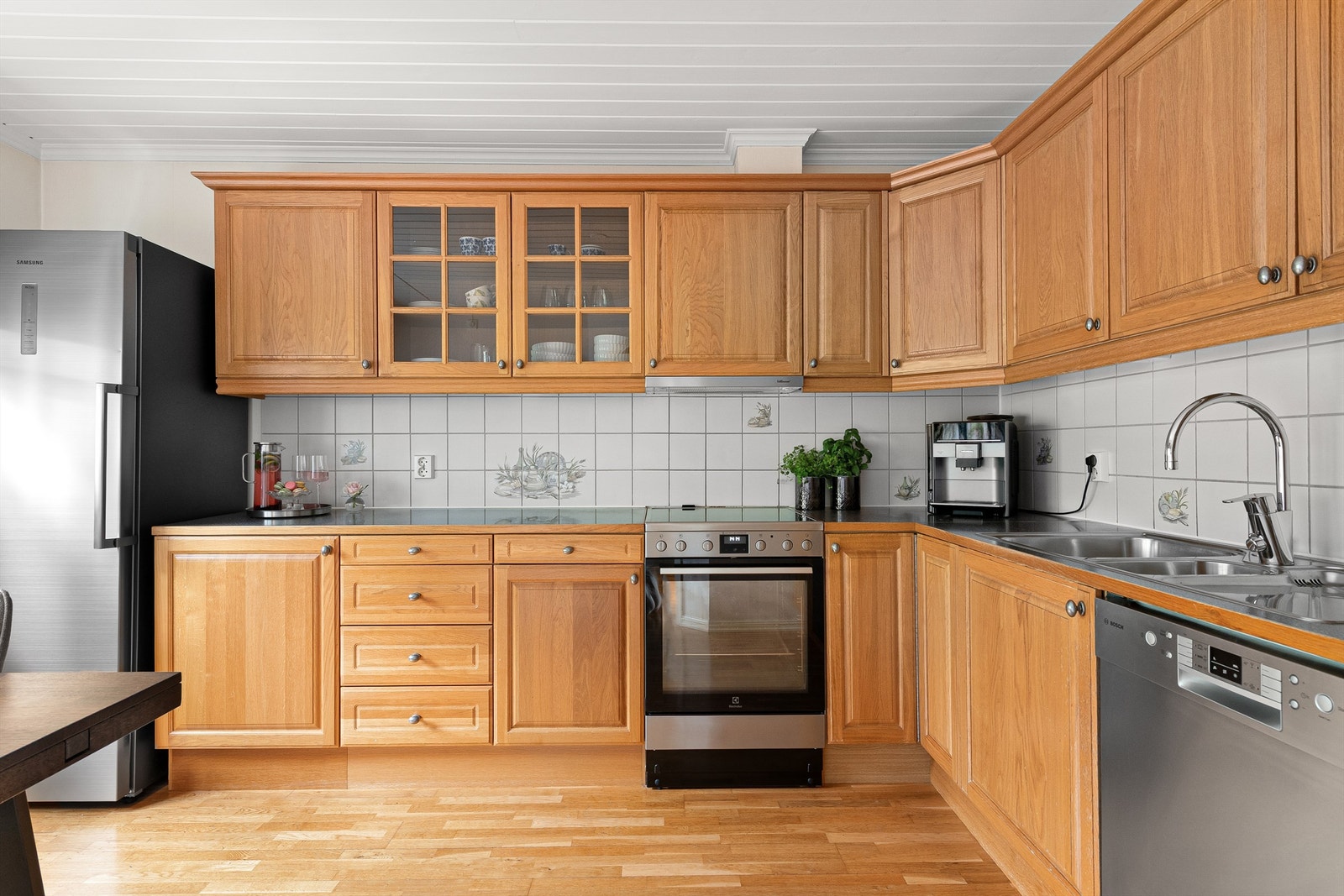 Kjøkkeninnredning fra Sigdal med profilerte eikefronter. Fliser mellom kjøkkenbenk og overskap Galleribilde