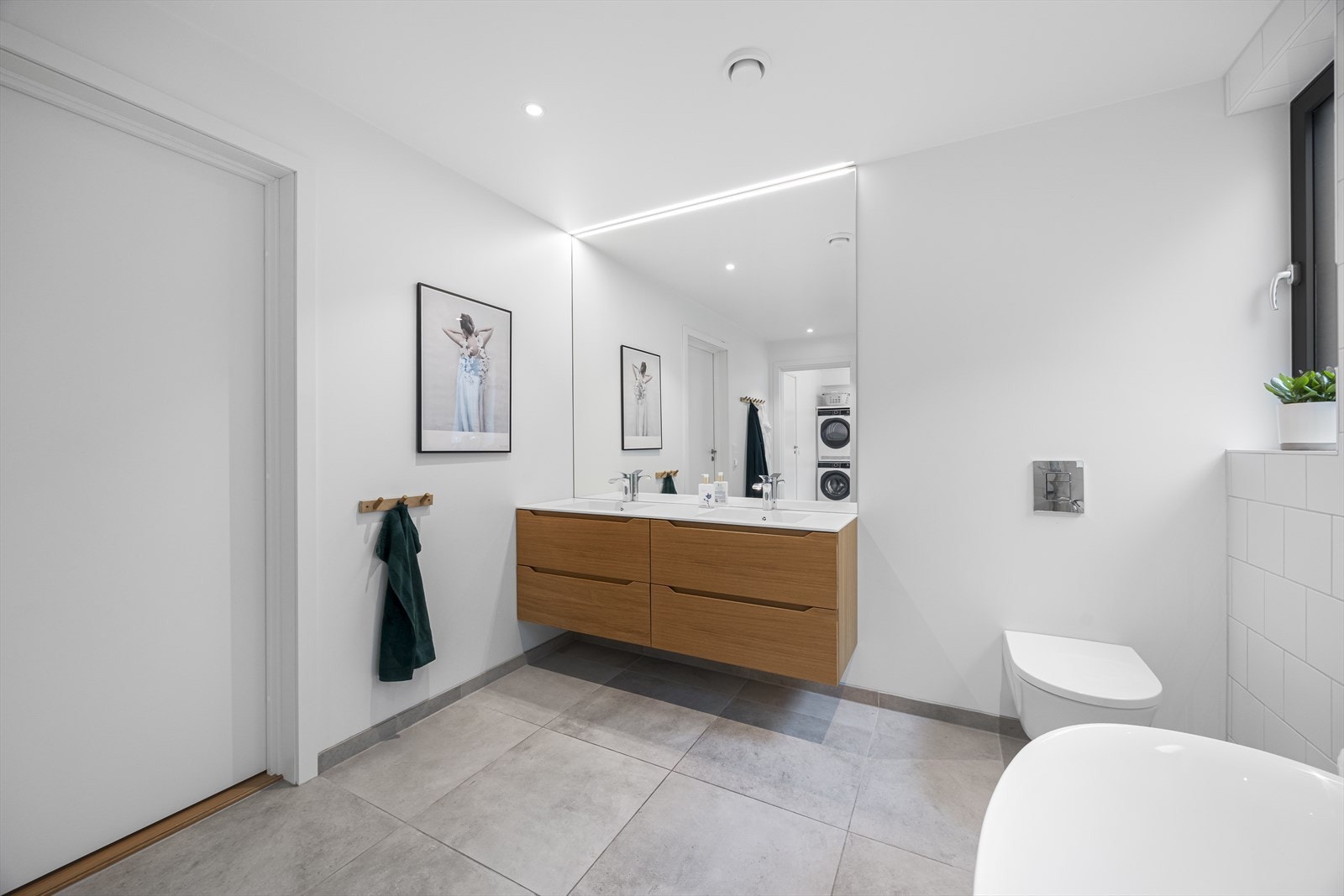 Stort hovedbad som er fliselagt til tak med ekstra store gulvfliser, vegghengt toalett, dusjnisje med glassvegger, badekar og dobbel servantinnrending fra Linn bad med Corian benkeplate. Galleribilde